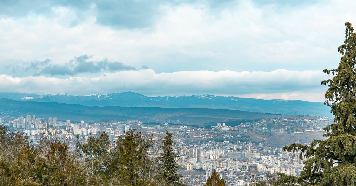 第比利斯及周邊山脈的空拍景觀，天空多雲。