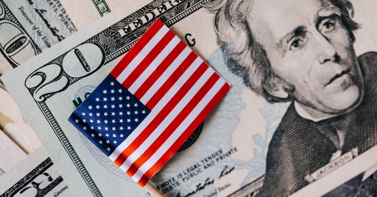 Altria and Philip Morris International sign contract manufacturing deal for combustible cigarettes From above of small American flag placed on stack of 20 dollar bills as national currency for business financial operations