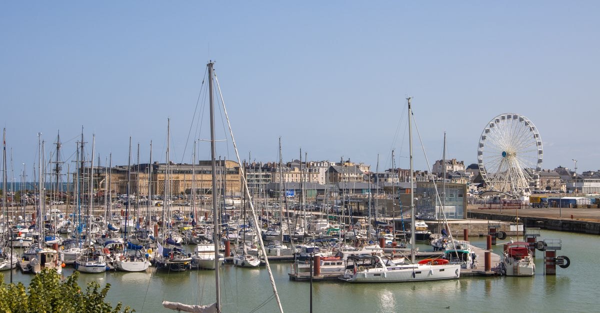 Saint Helier Travel Guide: Coastal Calm in Jersey's Capital Beautiful view of boats in Saint-Malo harbor, Brittany, France with a ferris wheel in the background under a clear sky.