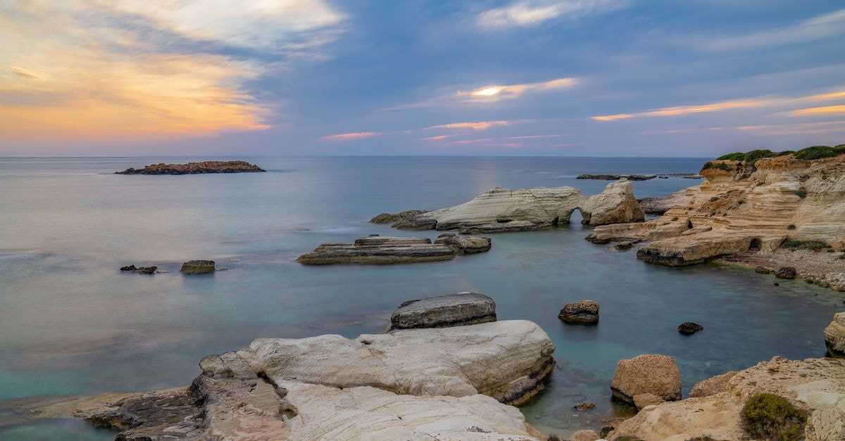 Larnaca Travel Guide: A Coastal Cyprus City With an Easy Walkable Heart Peaceful sunset over a rocky coastline with ocean view in Cyprus. Ideal for travel and nature themes.