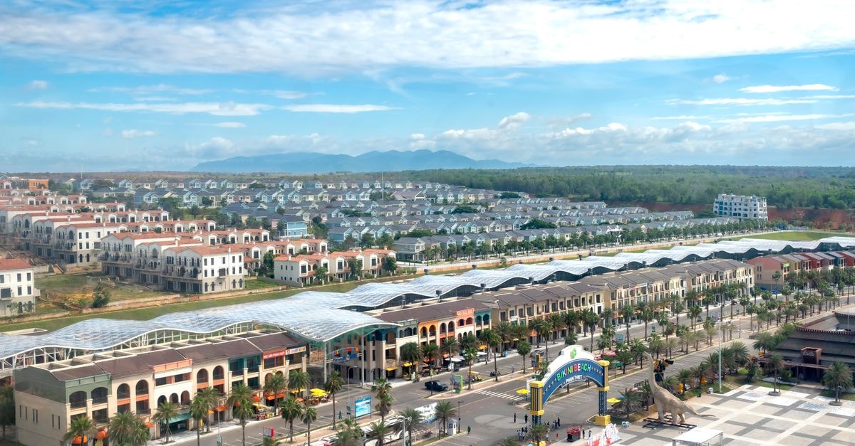 TownePlace Suites Olympia: Capitol-Adjacent Stay on Capitol Way A vibrant aerial view of a cityscape with an amusement park entrance, palm trees, and blue sky.