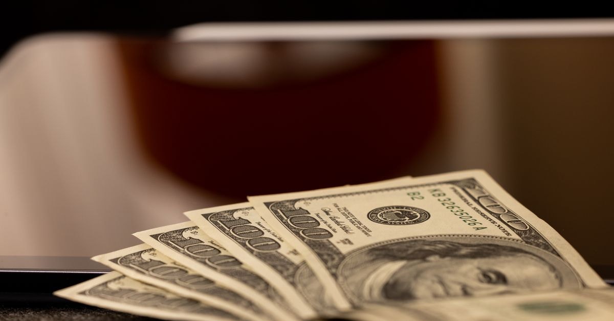 Hedge Funds and Banks Pile Into Caterpillar With Fresh Multimillion-Dollar Stakes Close-up image of multiple dollar bills placed beside a laptop, symbolizing finance and digital economy.