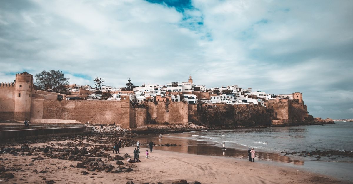 Le Pietri in Rabat: Urban Hotel Steps From the City Center A scenic view of an ancient fortified city with sandy beach and blue skies.