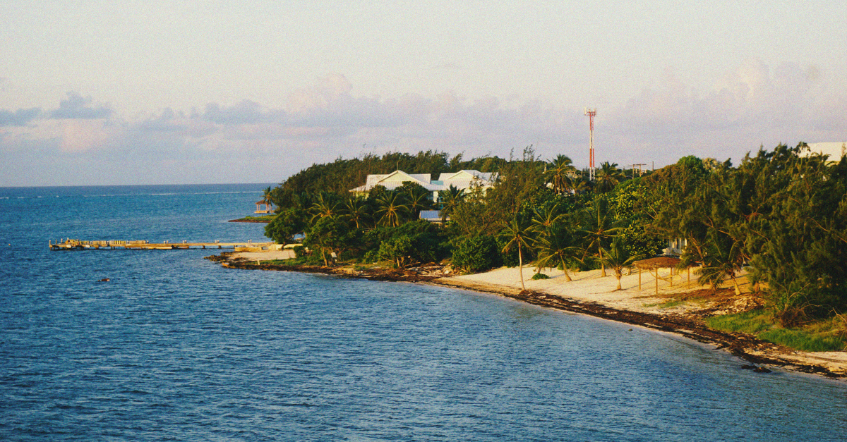 Manta House in Cockburn Town: A Duke Street Address in Turks and Caicos Serene tropical coastline with palm trees and ocean view at sunset, perfect for travel inspiration.