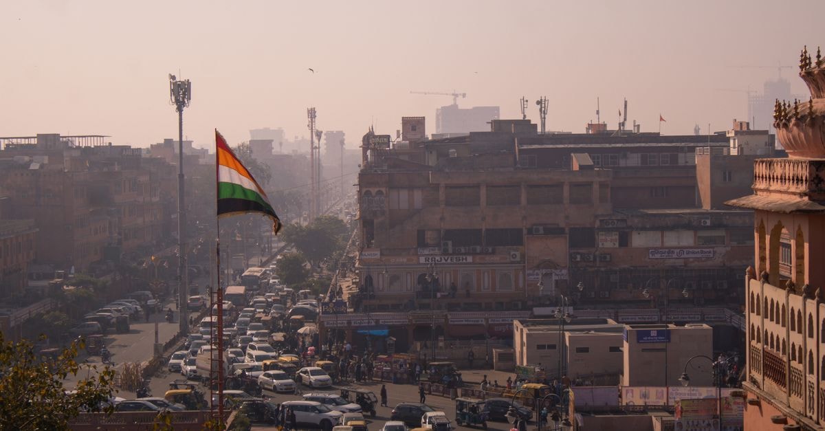 A busy street in Jaipur, India with the national flag waving, conveying a sense of vibrant city life.