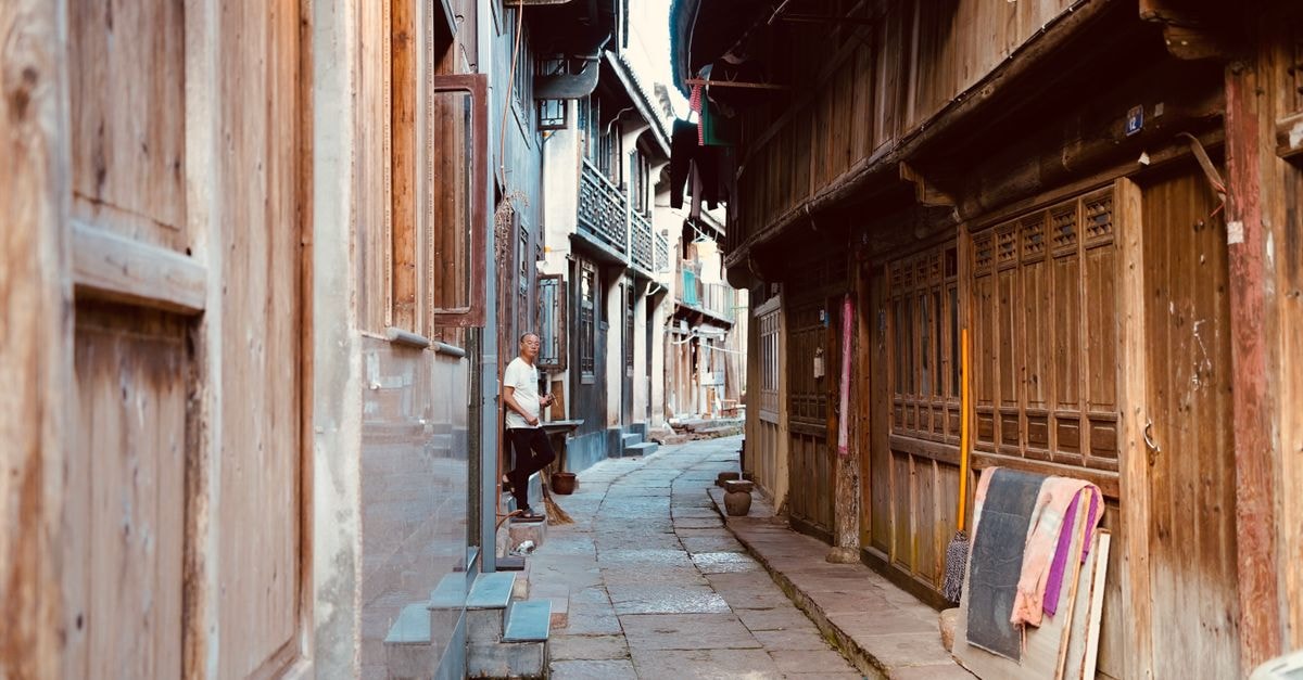 A narrow paved street with traditional wooden houses in an old rustic alleyway.