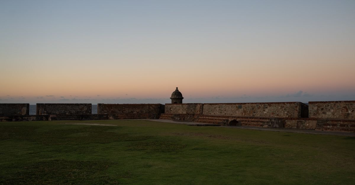 Peaceful sunset view of a historic fort in San Juan, Puerto Rico with clear skies.