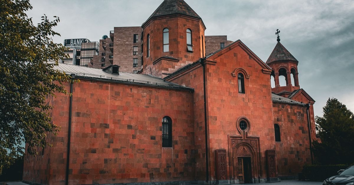Hotel de la Calle Real: A Centro Stay in Armenia A stunning red brick church with Byzantine influence stands against a cloudy sky in an urban environment.