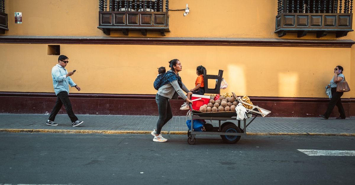 A woman pushes a cart with coconuts on a sunny street in Trujillo, Peru. Urban daily life scene.