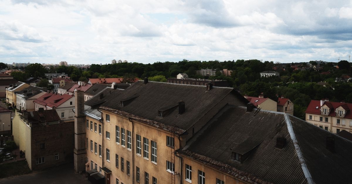 Aerial view of a European cityscape featuring historic buildings under a cloudy sky, with scenic greenery.