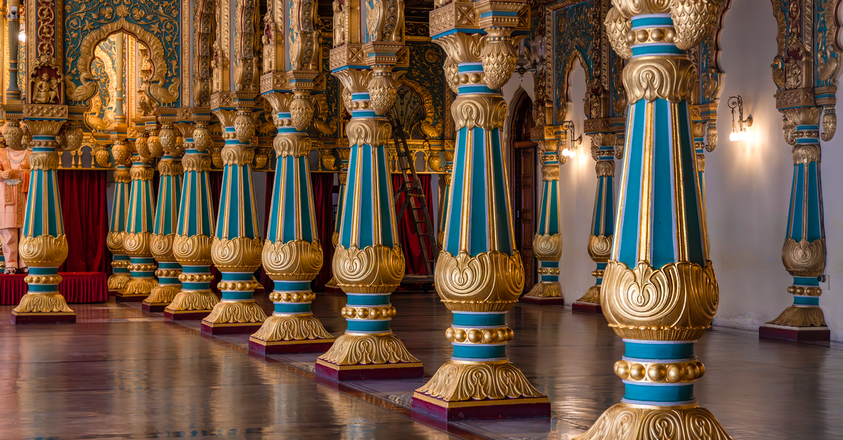 Explore the stunning intricacies of Mysore Palace's opulent interior, featuring lavishly decorated columns.