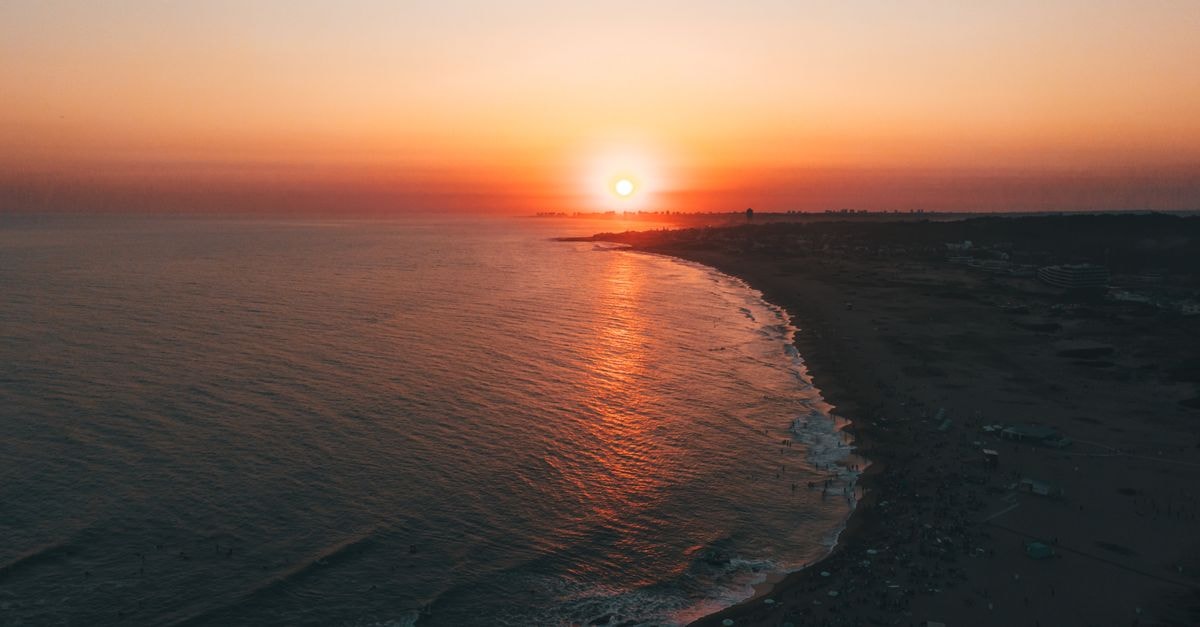 A breathtaking aerial view of a sunset over Punta del Este beach, casting warm hues on the ocean waves.