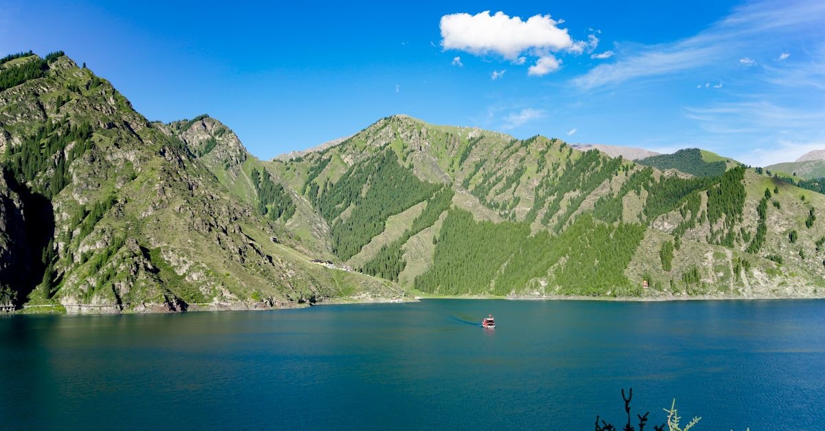 Artux Travel Guide: A Quiet Xinjiang Border Town to Explore Breathtaking view of lush green mountains surrounding a tranquil blue lake under a clear sky.