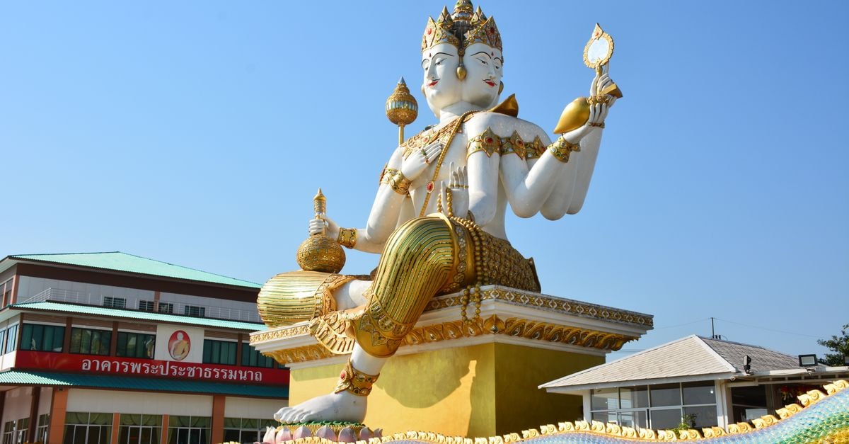 Budta Travel Guide: Getting Around, Arriving, and Eating Well Beautiful statue of a Hindu god under clear blue skies in Thailand, showcasing vibrant colors and intricate details.