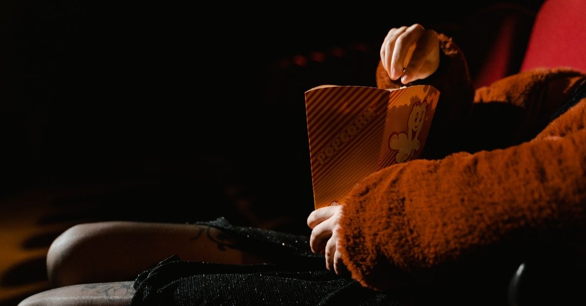 Spider-Man: Brand New Day Expands to IMAX After Weeklong Delay as The Odyssey Retains Premium Film Network A person enjoying popcorn during a movie at an indoor cinema, sitting comfortably.