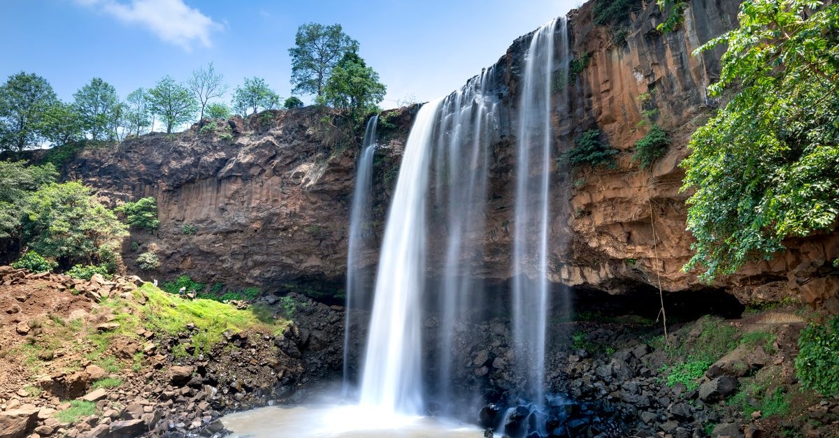 Malanje Travel Guide: Waterfalls, Rock Formations and Local Plates Beautiful waterfall cascading down a cliff in a tranquil and scenic forest landscape.