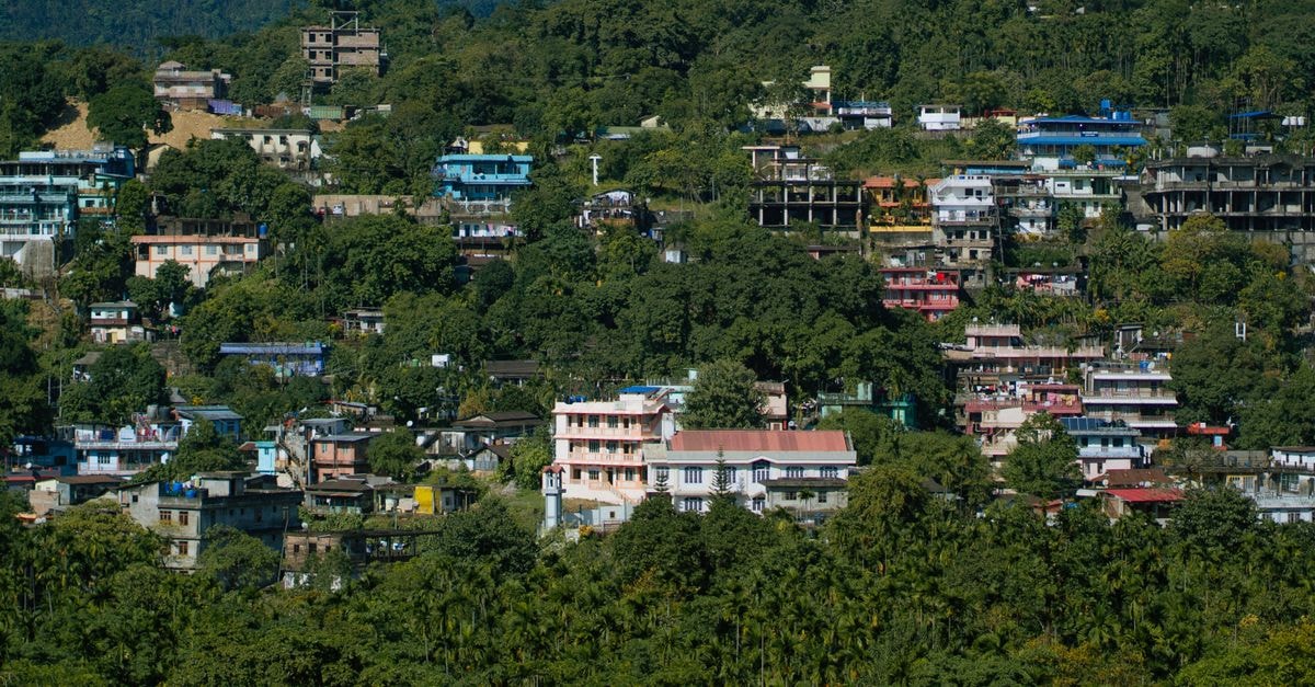 Itanagar Travel Guide: A Slow Look at Arunachal's Capital A vibrant hillside town with colorful buildings surrounded by lush greenery, showcasing a serene rural landscape.