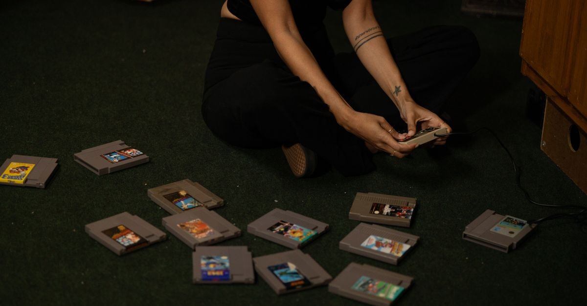 PS1 Exclusive 'The Drug Store' Stealth-Released on PS5 and Nintendo Switch 2 After 28 Years Adult woman sitting cross-legged, holding a vintage game controller, surrounded by retro game cartridges.