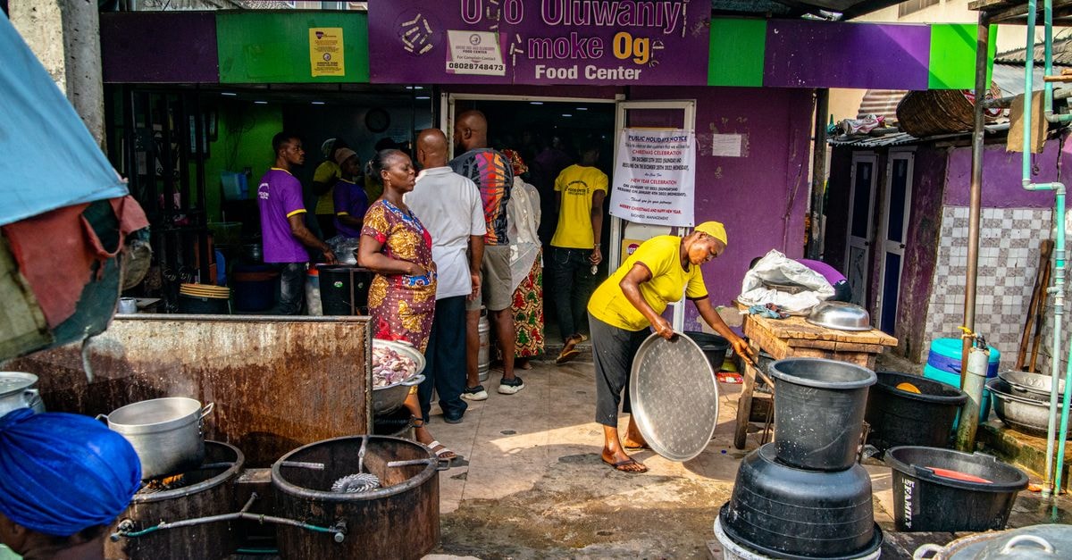 Ijebu Ode Travel Guide: Getting There, Eating Well, and Settling In Outdoor scene of people at a local food center, bustling with activity and vibrant colors.