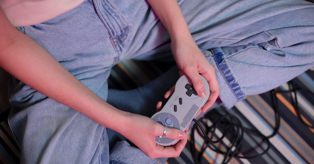 Sony sets Pulse Elevate pre-orders for September 1 and launch for November 12 Close-up of a young woman holding a retro game controller indoors, enjoying gaming.