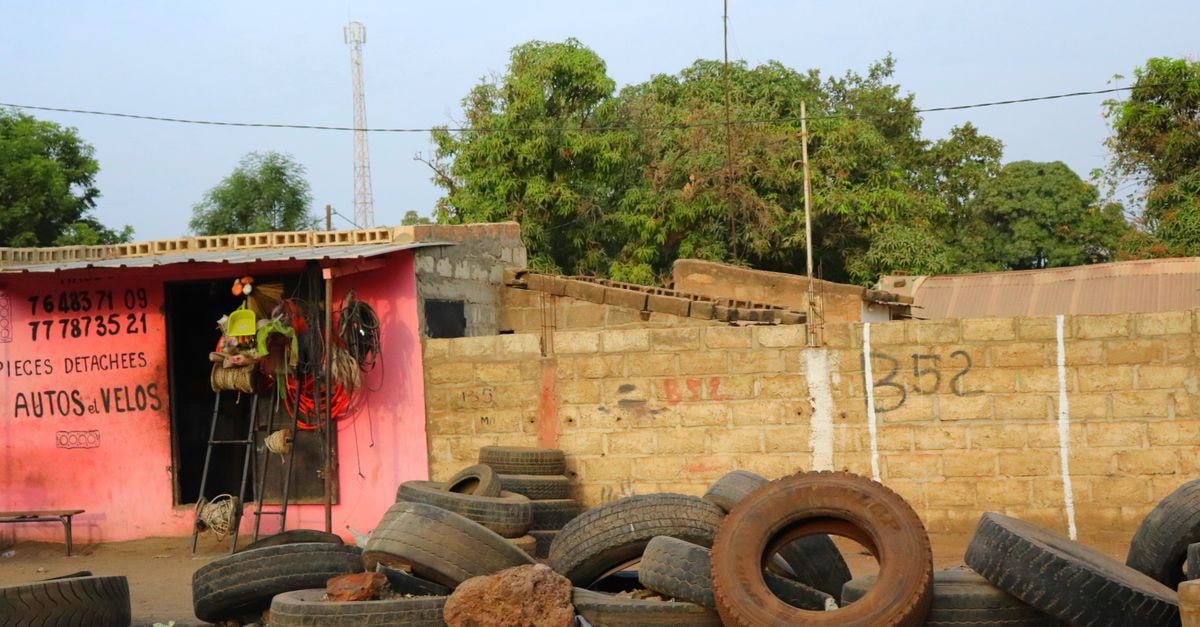 Tambacounda Travel Guide: Senegal's Sahelian Crossroads Roadside tire shop with worn tires and brick wall, Senegal.