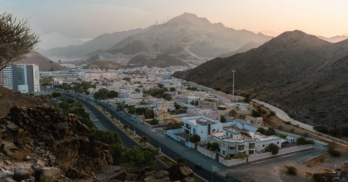 Bawshar Travel Guide: Planning Tips, Costs and Things to Do Discover the tranquil beauty of Khor Fakkan, UAE with this stunning aerial view at sunset.