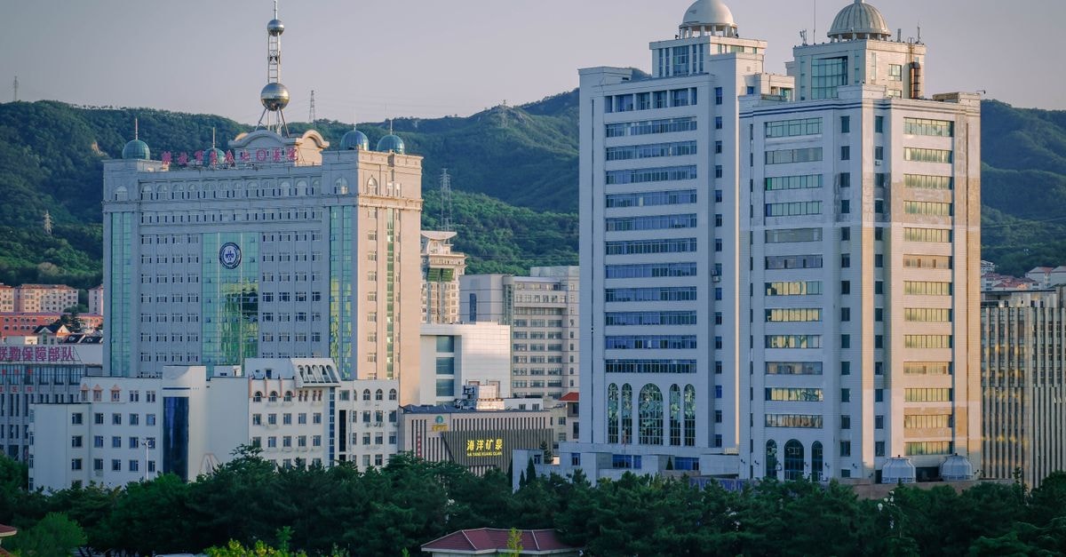 Jeco Hotel in Dassa-Zoumé: An Architectural Landmark Among the 41 Hills Urban cityscape with modern high-rise buildings and lush greenery at dusk.