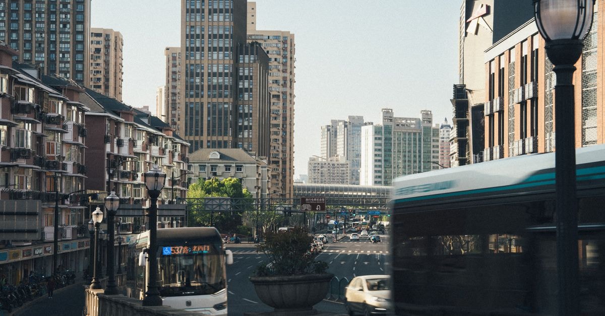 Yantai travel guide: coastal charm, scenic buses, and easy planning tips Dynamic city scene capturing buses and traffic amidst towering skyscrapers in daylight.