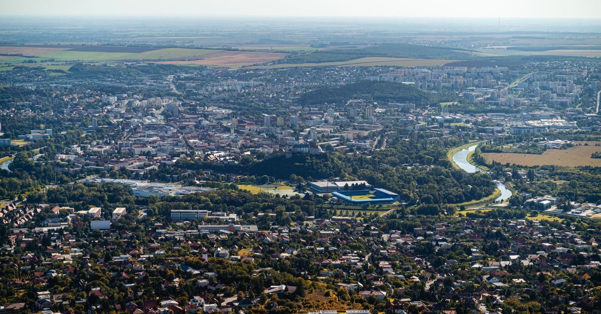Stunning aerial shot of Nitra city with lush greenery and a winding river on a sunny day.
