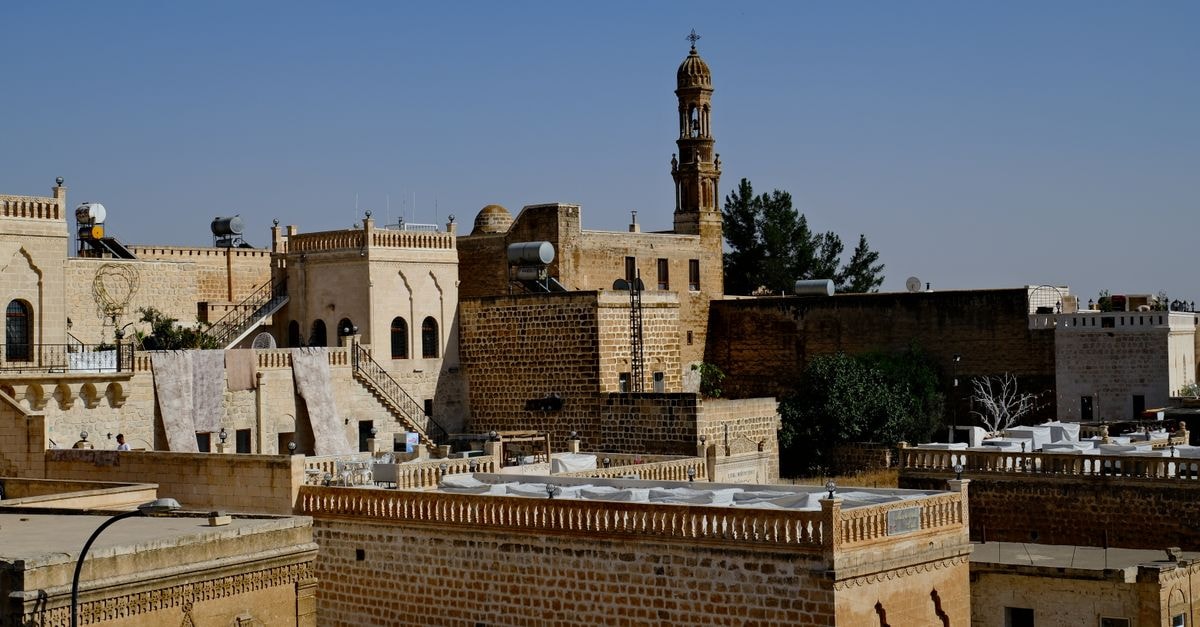 Aerial view of the historic architecture of Mardin, Türkiye, showcasing traditional stone buildings and iconic structures.