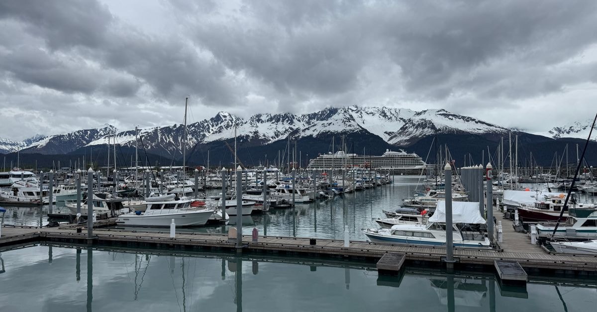 Anchorage Travel Guide: Tips for a Real Alaska City Stay Scenic view of Seward Harbor with boats and snow-capped mountains under a cloudy sky.