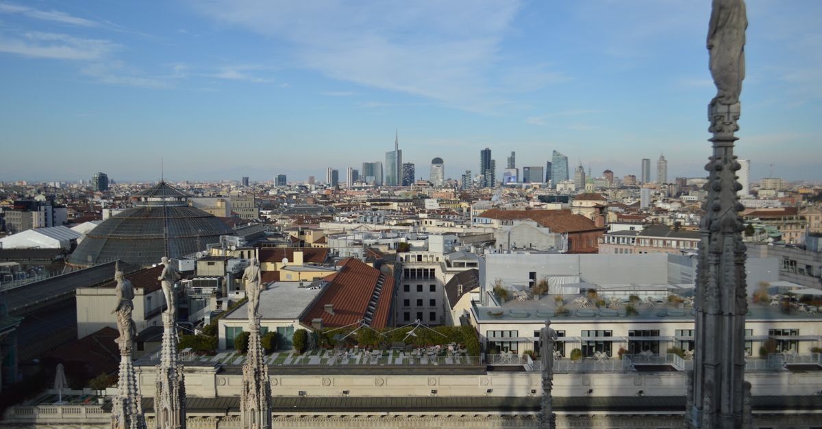 TownHouse Duomo Milano: 5-Star Rooms With Piazza Duomo Balconies Captivating aerial view of Milan's skyline from atop the Duomo with a clear blue sky backdrop.