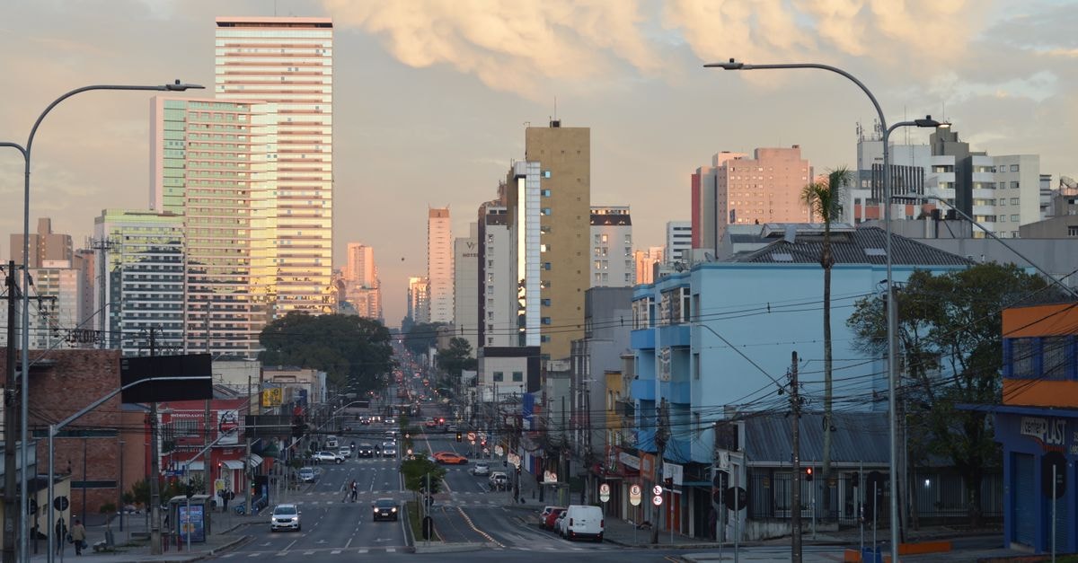 Curitiba Travel Guide: Planning Tips, Costs and Things to Do Urban skyline of Curitiba, Brazil, captured at sunset featuring high-rise buildings and city streets.