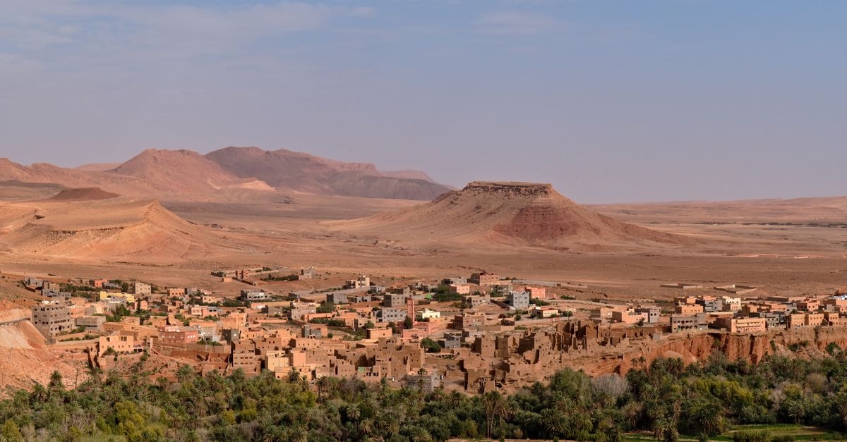 Faya-Largeau Travel Guide: Desert Calm and Oasis Flavors Aerial view of a traditional Moroccan town in a desert landscape with mountains.
