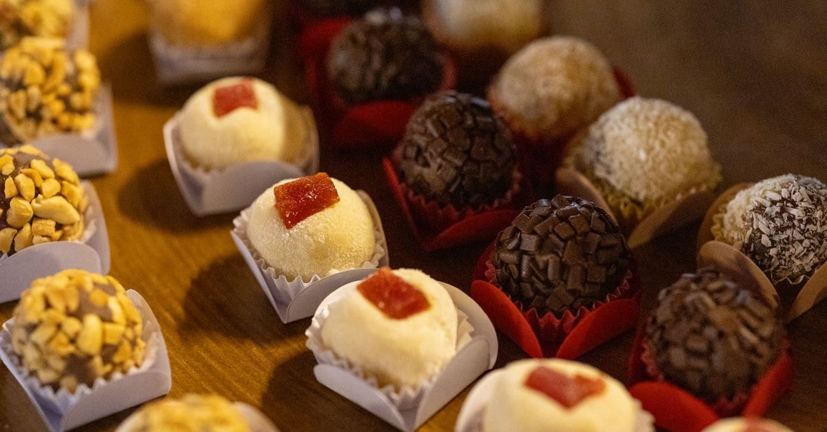 Close-up of assorted Brazilian brigadeiros displayed on a wooden table, showcasing a variety of flavors and textures.
