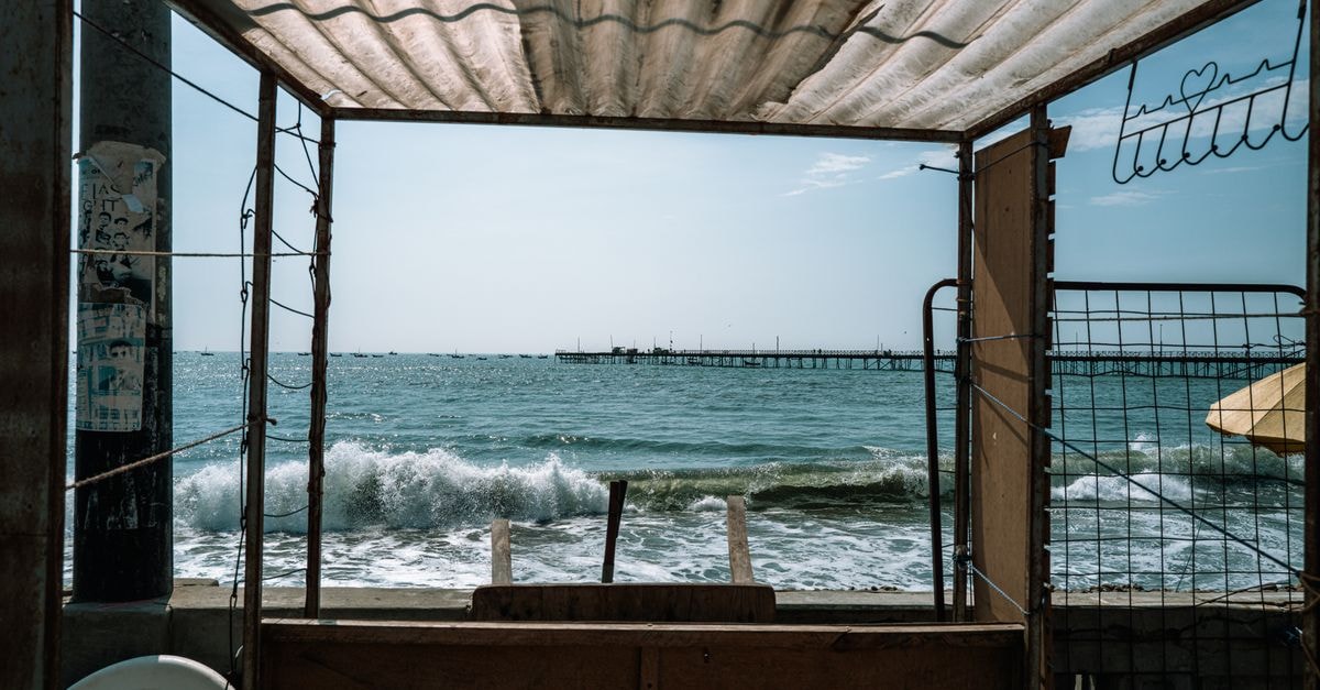 A picturesque view of the ocean waves crashing on the shore from a rustic beachfront structure in Pacasmayo, Peru.