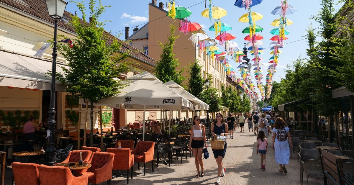 Vibrant umbrellas decorate a lively street in Bjelovar, Croatia, creating a festive atmosphere.
