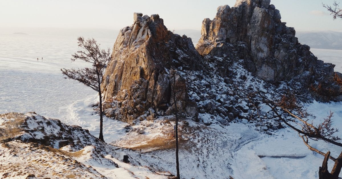Snow-covered rock formation with trees in a winter landscape, Russia.