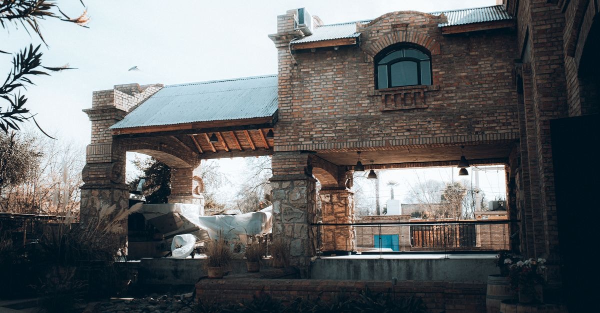 A rustic brick winery building under a clear sky, showcasing Mendoza's architectural charm.