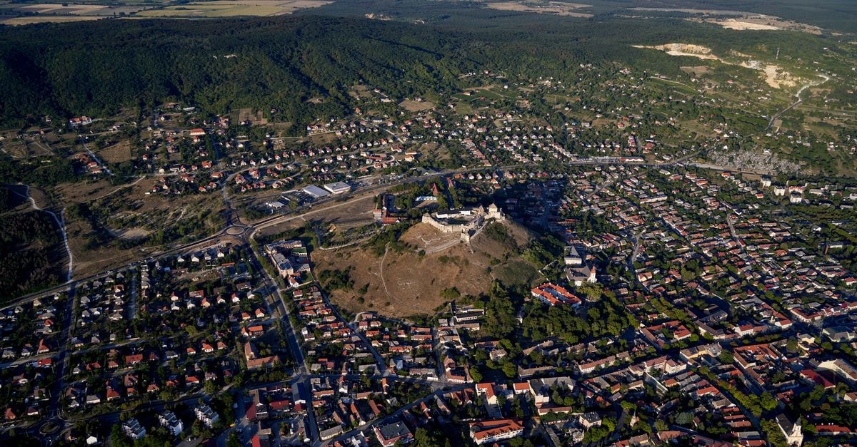 Győr Travel Guide: Planning Tips, Costs and Things to Do Stunning aerial view of Sümeg Castle and residential areas in Hungary during daylight.