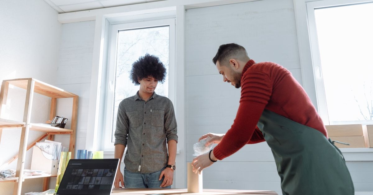 Silgan Holdings: Earnings Power Visible, but the Dated Price Already Prices It In Two adults collaborating at a standing desk in a bright office with a laptop and packaging materials.