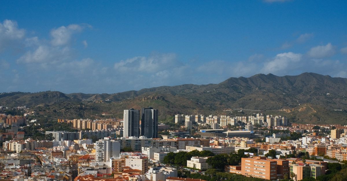 Hotel Ceuta Puerta de África in Ceuta: A Front-Row Stay at Spain's African-Gate Address A panoramic view of Málaga with urban architecture and distant mountains under a clear blue sky.