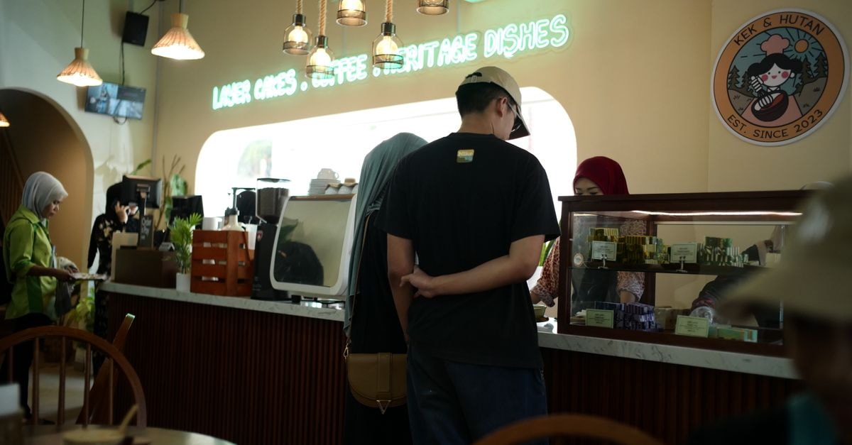 Perdana Hotel Kota Bharu in Kota Bharu: Merdeka Flavours and Late Stays Warm interior of a bustling coffee shop in Kota Bharu with customers and staff interaction.