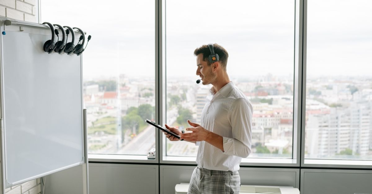 Fortinet launches free two-year high school cybersecurity curriculum for U.S. schools Man with headset and tablet in office by a whiteboard and large windows overlooking cityscape.