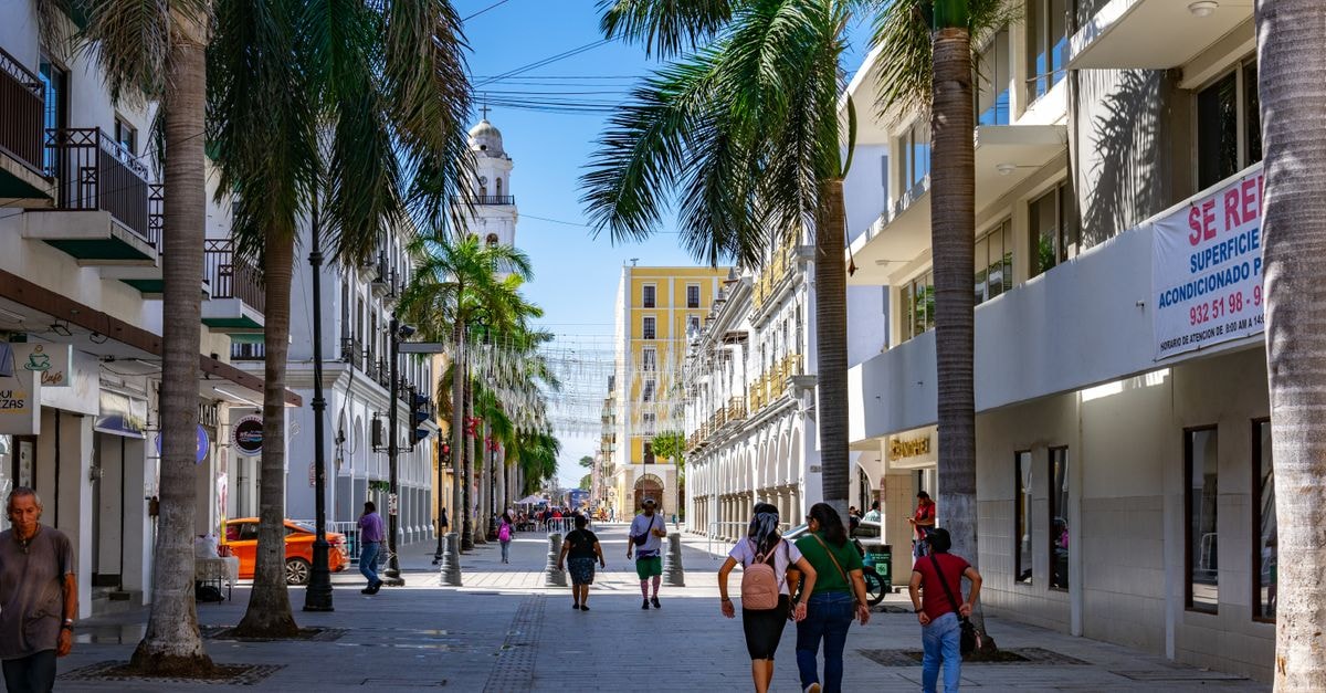 Mérida Travel Guide: Easy Arrivals, Walkable Centro, Bold Flavors Daytime street view in Veracruz, Mexico with people, palm trees, and colonial architecture.