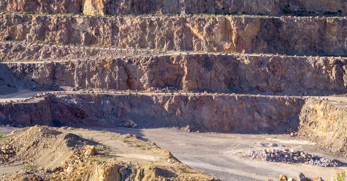 Silver rebounds after sharp pullback as Treasury move weakens dollar, with rate-cut expectations in focus Sunlit view of a rugged, multi-layered rock quarry with exposed strata and rocky terrain.