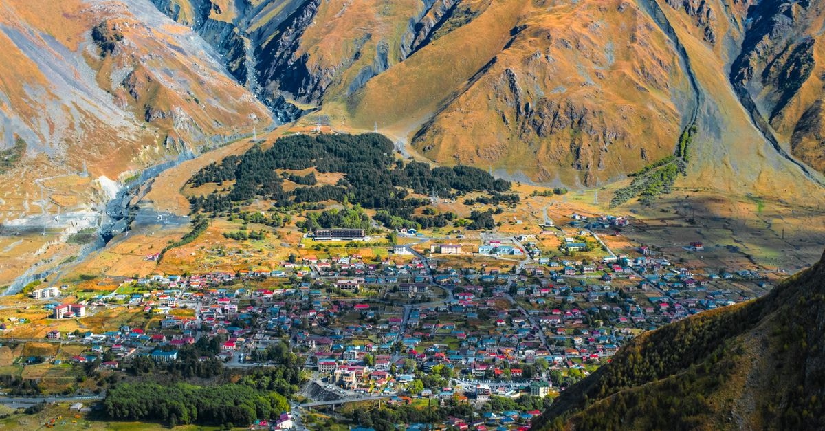 Barnaul Travel Guide: Planning Tips, Costs and Things to Do Aerial view of a colorful village nestled in mountainous terrain during autumn.