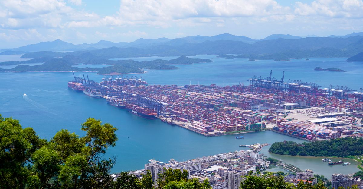 Tungsten Market Surges on Chinese Export Curbs as Western Producers Seek New Supply Aerial image of a bustling industrial port with containers in a scenic coastal setting.