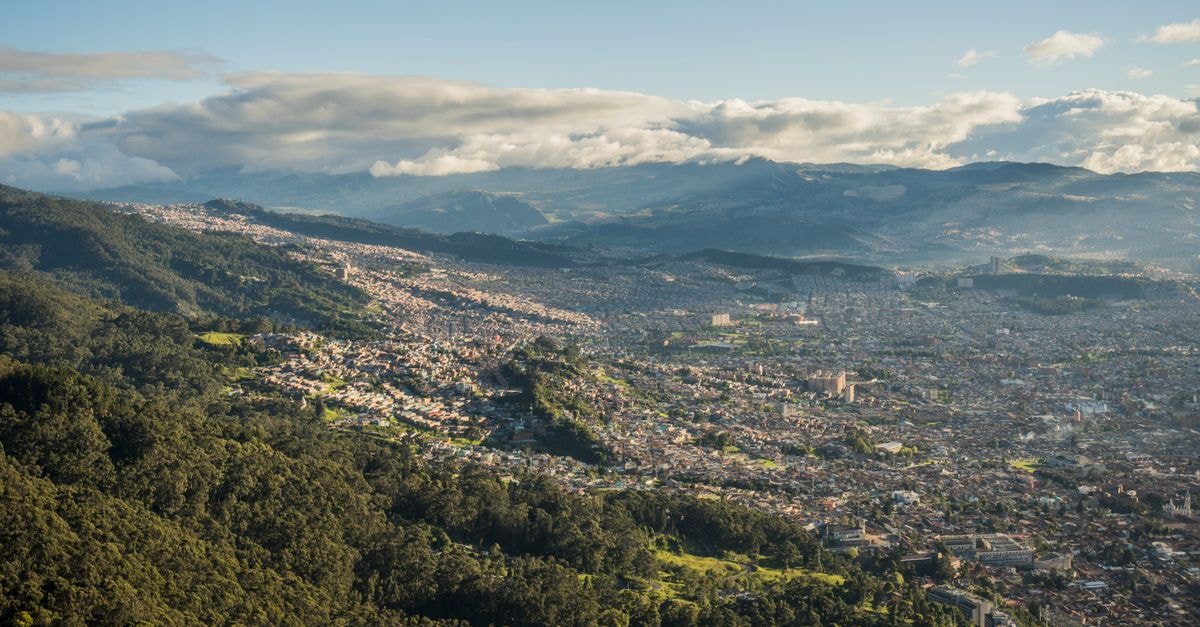Nican Resort in Bunamwaya: A Serene Escape with Spa, Dining and Event Spaces Aerial shot of Bogotá, Colombia, showcasing cityscape and surrounding lush mountains.