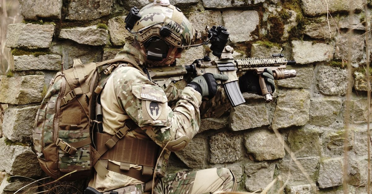 Boeing wins $20 billion U.S. Navy contract to build F/A-XX sixth-generation carrier fighter Soldier in camouflage gear aims a rifle while hiding along a stone wall outdoors.